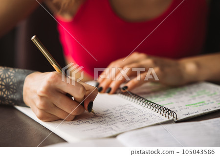 Close-up woman's hand holding a pencil and writing information in a notebook 105043586