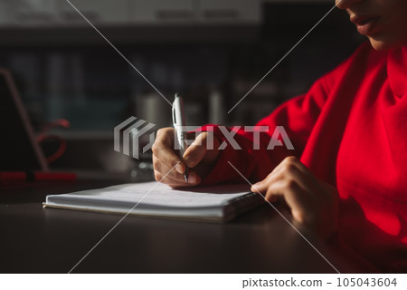 Close-up woman's hand holding a pencil and writing information in a notebook 105043604