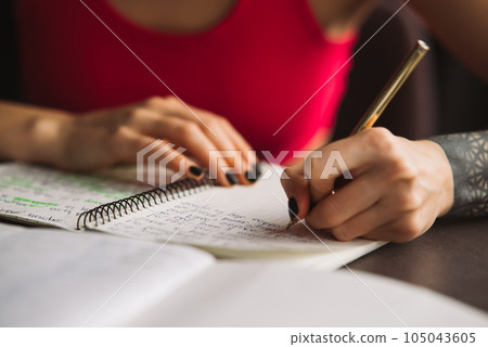 Close-up woman's hand holding a pencil and writing information in a notebook 105043605