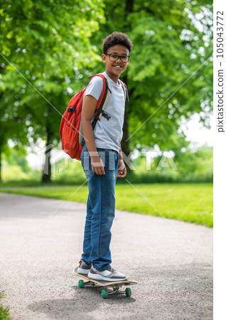 A curly-haired boy on a longboard in the park A curly-haired boy on a longboard in the park 105043772
