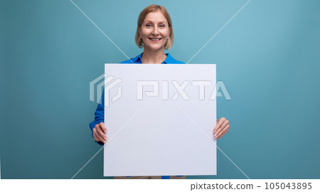 blonde middle aged woman holding note board with mockup on blue background copy space 105043895