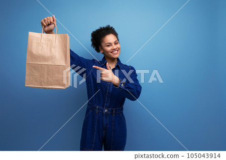 happy positive activist young hispanic brunette woman with fluffy curly hair in blue denim suit 105043914
