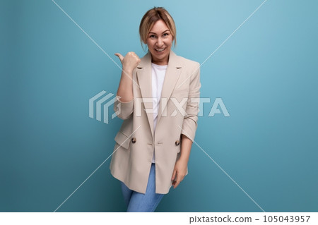 charming blonde young adult in jacket smiling on studio background 105043957
