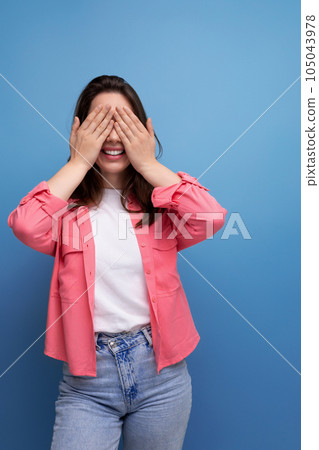 smiling brunette woman with hair below her shoulders in a shirt closed her hands in anticipation of smiling brunette woman with hair below her shoulders in a shirt closed her hands in anticipation of 105043978