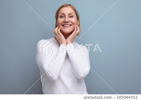 blond pensive middle-aged woman in a white sweater 105044352