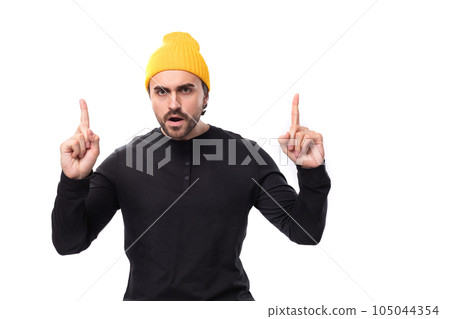 an attractive young 30 year old guy with a beard dressed in a black jacket and a yellow hat tells 105044354