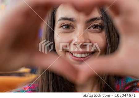 Happy young woman girl makes symbol of love showing heart sign to camera express romantic feelings Happy young woman girl makes symbol of love showing heart sign to camera express romantic feelings 105044671