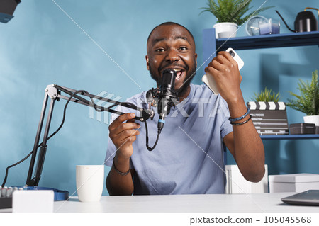 Excited african american blogger sharing positive insight with internet channel subscribers. Happy cheerful vlogger giving good news to audience while filming video for blog 105045568