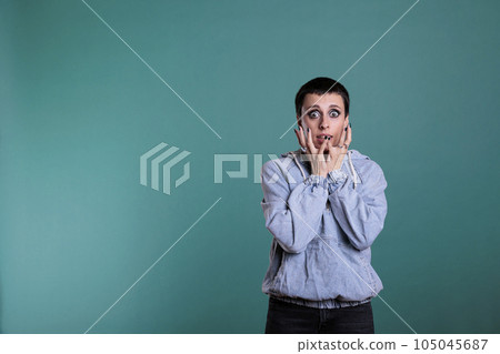 Afraid nervous woman having terrified expression after hearing the news, terrified person standing in studio posing over isolated background. Frightened female looking at camera with shock reaction 105045687