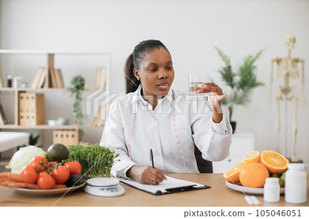 Nutrition specialist checking fluid in glass at workplace 105046051