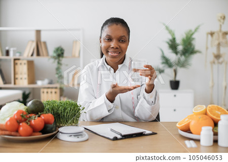 Lady with glass of water posing at office desk in clinic 105046053