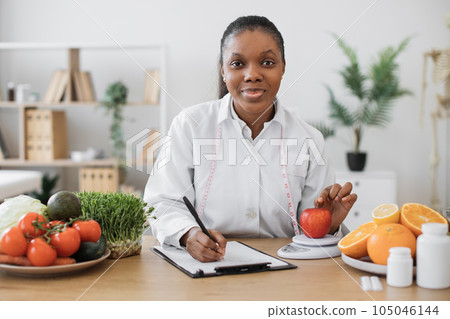 Professional assessing apple on scales in consulting room 105046144