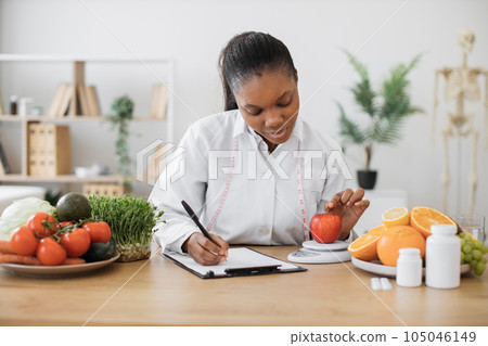 Professional assessing apple on scales in consulting room 105046149