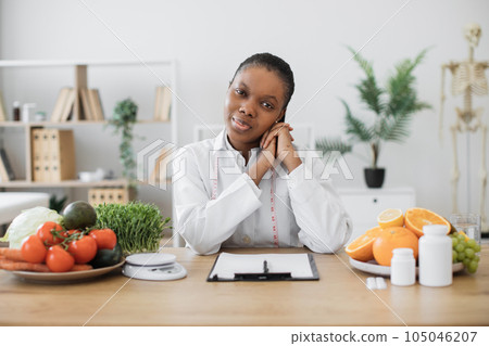 Lady in lab coat looking at camera in dietitian's office 105046207