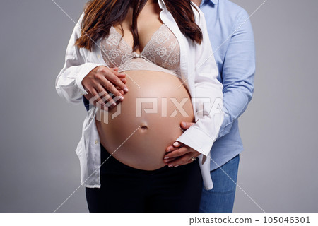 Pregnant woman and her husband holding hands together on her belly. Happy pregnancy concept. 105046301