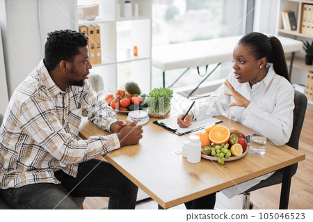 Expert in diet talking to man in consulting room of hospital 105046523