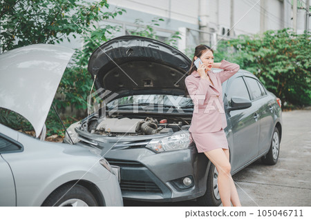 female motorist is calling an insurance or recovery service officer for assistance related to a car accident. 105046711