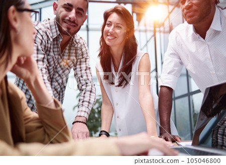 Colleagues lean on the conference table and discuss business, app UI and design. 105046800