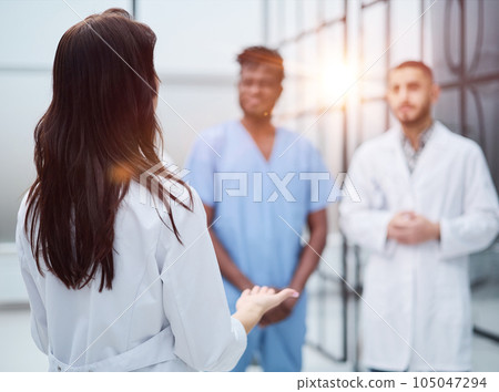 medic woman stands with her back and instructs with colleagues 105047294