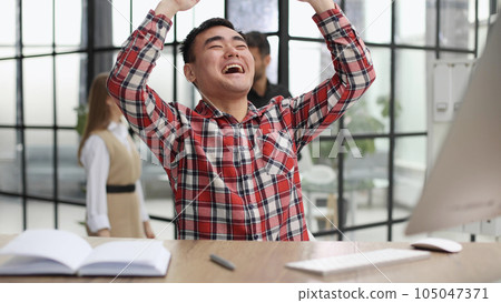 Happy young Asian man sitting in the office at the table 105047371