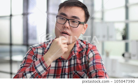 a young investor in casual clothes sits at a table and thinks about profit 105047390