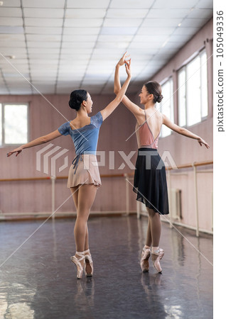 Two Asian ballerinas are dancing in the class.  105049336