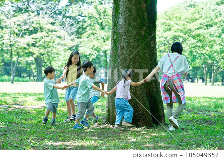 Children and women holding hands and going around the tree 105049352