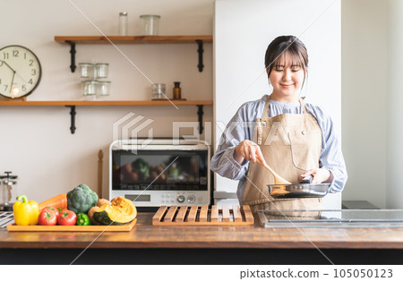 圍裙的女人/家庭主婦在廚房裡使用煎鍋(微笑) 圍裙的女人/家庭主婦在廚房裡使用煎鍋(微笑) 105050123