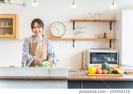 A woman / housewife in an apron who does the washing (smile) A woman / housewife in an apron who does the washing (smile) 105050128