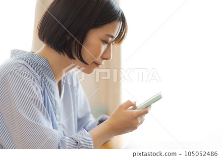 Portrait of a woman looking at a smartphone Portrait of a woman looking at a smartphone 105052486