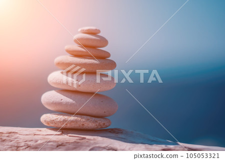 Pyramid stones on the seashore on a sunny day on the blue sea background. Happy holidays. Pebble beach, calm sea, travel destination. Concept of happy vacation on the sea, meditation, spa, calmness. 105053321