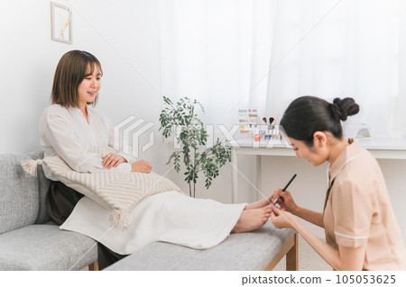 一位女士和一位美甲師在美甲沙龍做修腳和腳趾甲 105053625