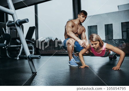 Sportive woman doing plank exercise training back and press muscles with trainer. Sport fitness workout strength power concept. 105054795