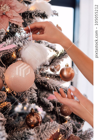 Woman hangs a Christmas ball on a Christmas tree. New Year's toy in women's hand 105055212