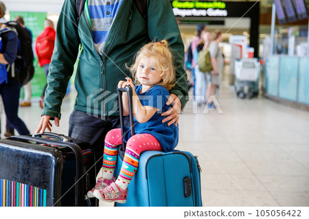 Cute little toddler girl and father at the airport. Happy family traveling by plane, making vacations. Young dad and baby daughter with suitcases waiting for flight. Family going on journey. Ireland Cute little toddler girl and father at the airport. Happy family traveling by plane, making vacations. Young dad and baby daughter with suitcases waiting for flight. Family going on journey. Ireland 105056422
