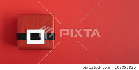Red Santa gift box with black belt on red background. Top view, copyspace. Red Santa gift box with black belt on red background. Top view, copyspace. 105056829