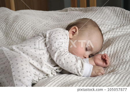 Peaceful adorable baby sleeping on his bed at home. Sleeping newborn baby concept. One year old baby girl sleeps peaceful at domestic room interior background. A serene dream. Face Close Up Peaceful adorable baby sleeping on his bed at home. Sleeping newborn baby concept. One year old baby girl sleeps peaceful at domestic room interior background. A serene dream. Face Close Up 105057877
