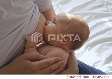 Mother breastfeeding baby at home. Mom nursing infant nurturing. Portrait of Child suckling milk from breast. Authentic shot of mother is breastfeeding her newborn baby. Close Up. Concept of maternity Mother breastfeeding baby at home. Mom nursing infant nurturing. Portrait of Child suckling milk from breast. Authentic shot of mother is breastfeeding her newborn baby. Close Up. Concept of maternity 105057885