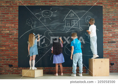 Little boys and girls, children drawing on blackboard, spending time together, studying, learning, playing 105058500