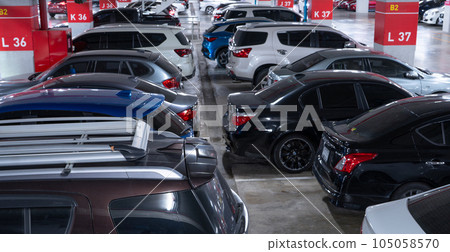 Busy underground car parking lot. Organized rows of vehicles in an urban hub. Urban convenience. Crowded parking space underground of the exhibition and convention center. Indoor car parking lot. 105058570