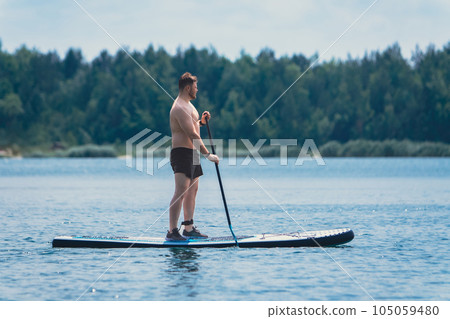 man standing on the supboard on the middle of the lake 105059480