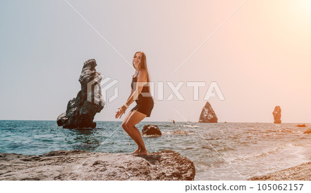 Woman summer travel sea. Happy tourist in hat enjoy taking picture outdoors for memories. Woman traveler posing on the beach at sea surrounded by volcanic mountains, sharing travel adventure journey Woman summer travel sea. Happy tourist in hat enjoy taking picture outdoors for memories. Woman traveler posing on the beach at sea surrounded by volcanic mountains, sharing travel adventure journey 105062157