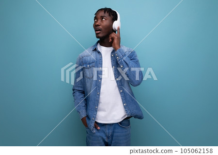 charismatic african man with dreadlocks in a denim jacket listening to music on headphones charismatic african man with dreadlocks in a denim jacket listening to music on headphones 105062158