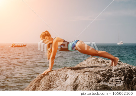 Woman sea yoga. Happy woman meditating in yoga pose on the beach, ocean and rock mountains. Motivation and inspirational fit and exercising. Healthy lifestyle outdoors in nature, fitness concept. Woman sea yoga. Happy woman meditating in yoga pose on the beach, ocean and rock mountains. Motivation and inspirational fit and exercising. Healthy lifestyle outdoors in nature, fitness concept. 105062160