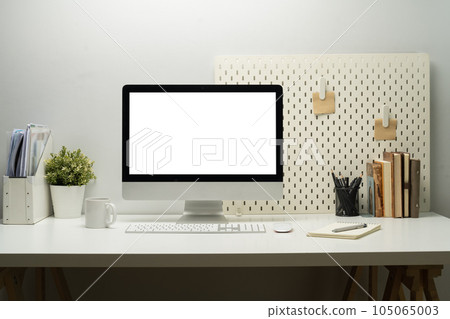 Blank empty desktop computer, potted plant and books on white table. White screen for your advertising text message  Blank empty desktop computer, potted plant and books on white table. White screen for your advertising text message  105065003