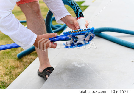 Man assembles a swimming pool vacuum cleaner. 105065731
