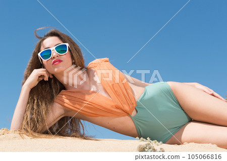 Young woman in swimsuits in the morning sun on the sand Young woman in swimsuits in the morning sun on the sand 105066816
