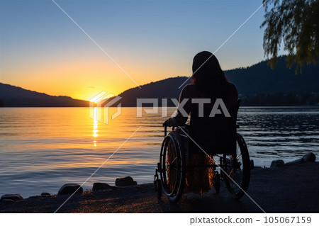 Disabled woman in wheelchair looking at the beach sunset. 105067159