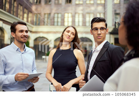 Business people, employees, colleagues standing outside office on street, lively talking. Cooperation, teamwork 105068345