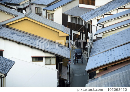 A rickshaw returning through the tiled roofs of Miyajima as dusk approaches 105068450